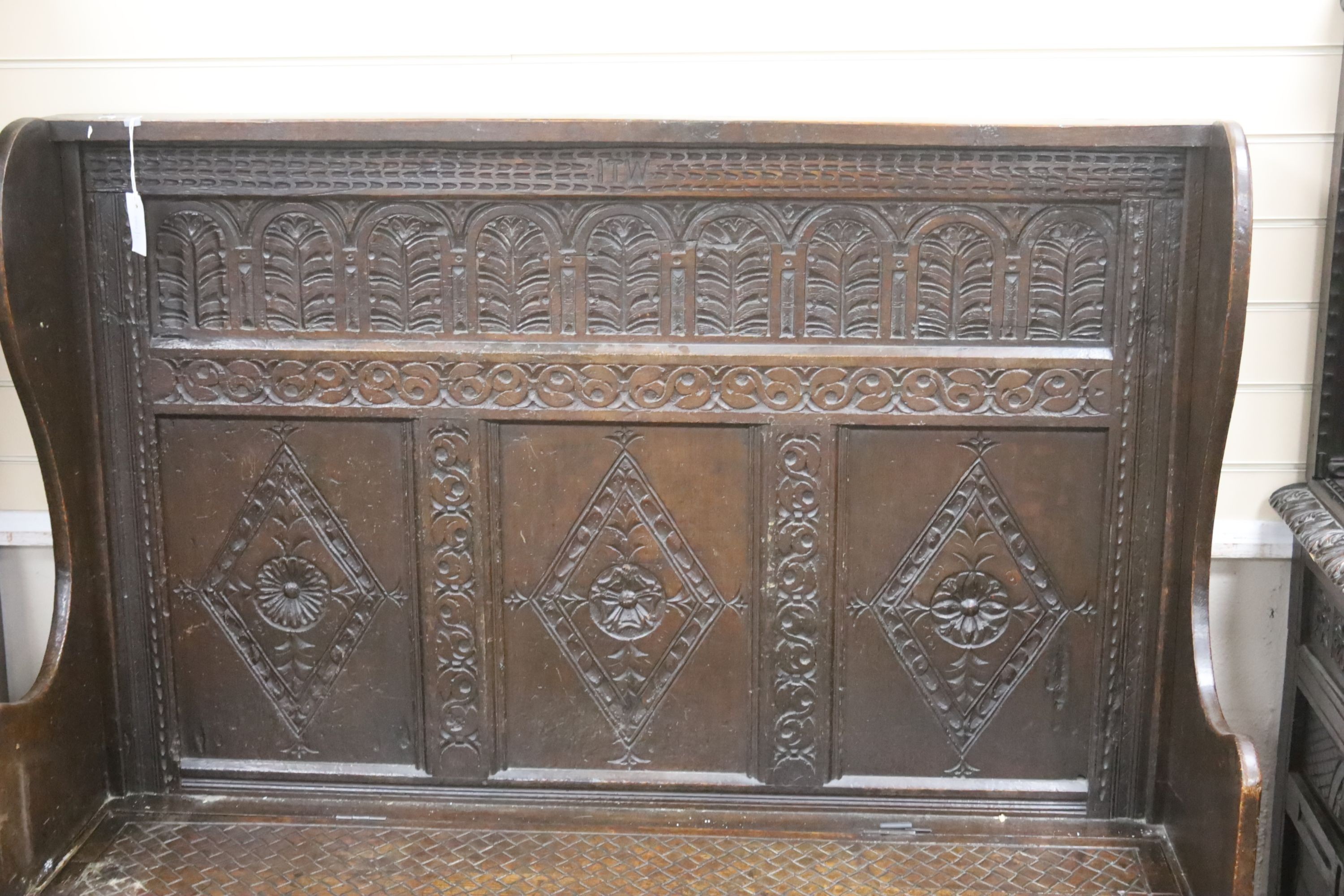An 18th century and later carved oak settle with hinged box seat, width 137, depth 42, height 137 cms.